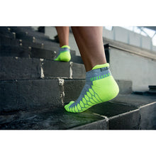 Load image into Gallery viewer, Man climbing stairs wearing Balega Silver No Show Midgrey/Neon Lime Socks
